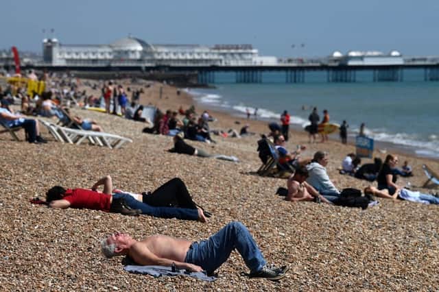 People relax on Brighton in southern England as temperatures rise across the country over the bank holiday weekend (Photo: GLYN KIRK/AFP via Getty Images)