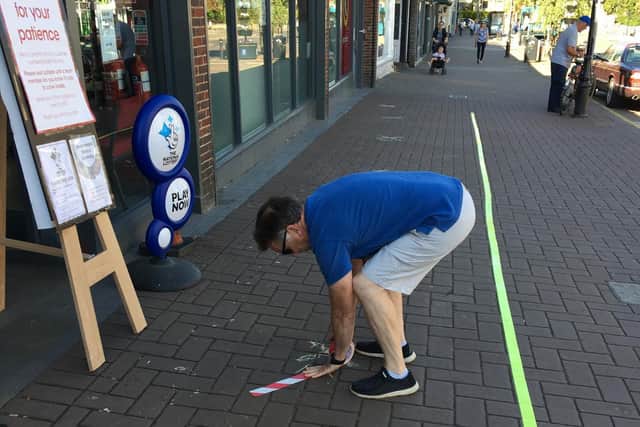 Cllr Gordon Perham marking up  the high street this morning with temporary tape to help the shops with queues to keep social distancing