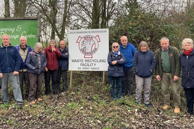 Annoyed residents stand by the waste recycling facility sign. Photo: Cllr Blamires.