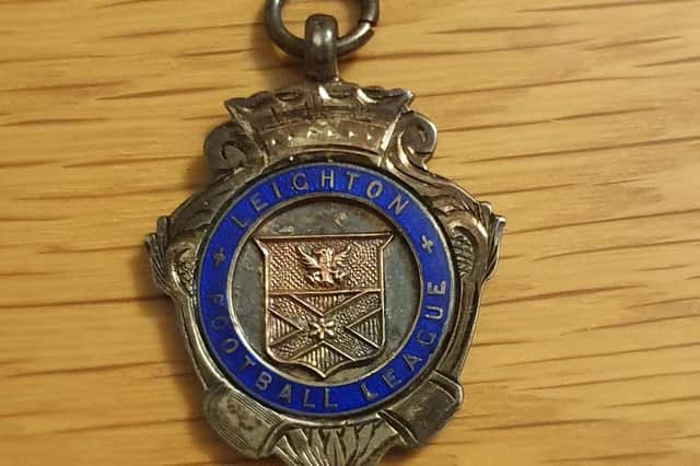 The watch fob badge bearing the Leighton Town Football League crest