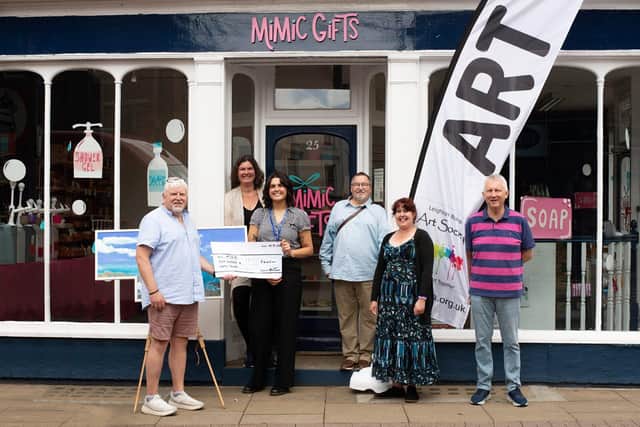 Huw Thomas presenting the cheque to Mind BLMK outside Mimic Gifts