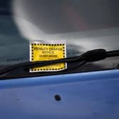 A Penalty Charge Notice (PCN) or parking ticket is pictured attached to the windscreen of a van  (Photo by DANIEL LEAL/AFP via Getty Images)