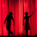 Silhouettes of three performers on stage.