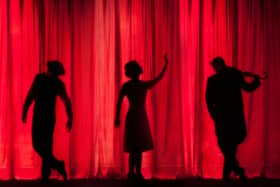 Silhouettes of three performers on stage.