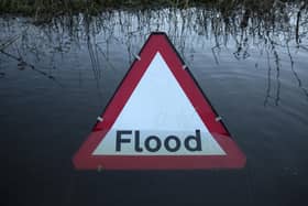 A flood warning road sign on a partially submerged road (Photo by Oli Scarff/Getty Images)