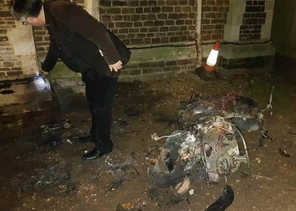 Reverend Dr Bernard Minton checking the cables and the burnt out moped. Photo by Richard Watts